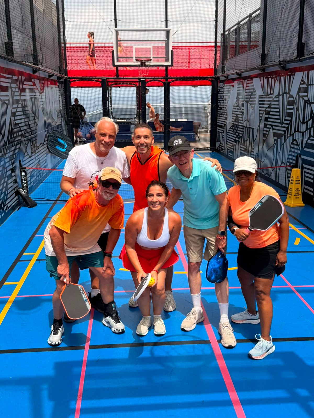 Group of travelers posing on the ship pickleball court